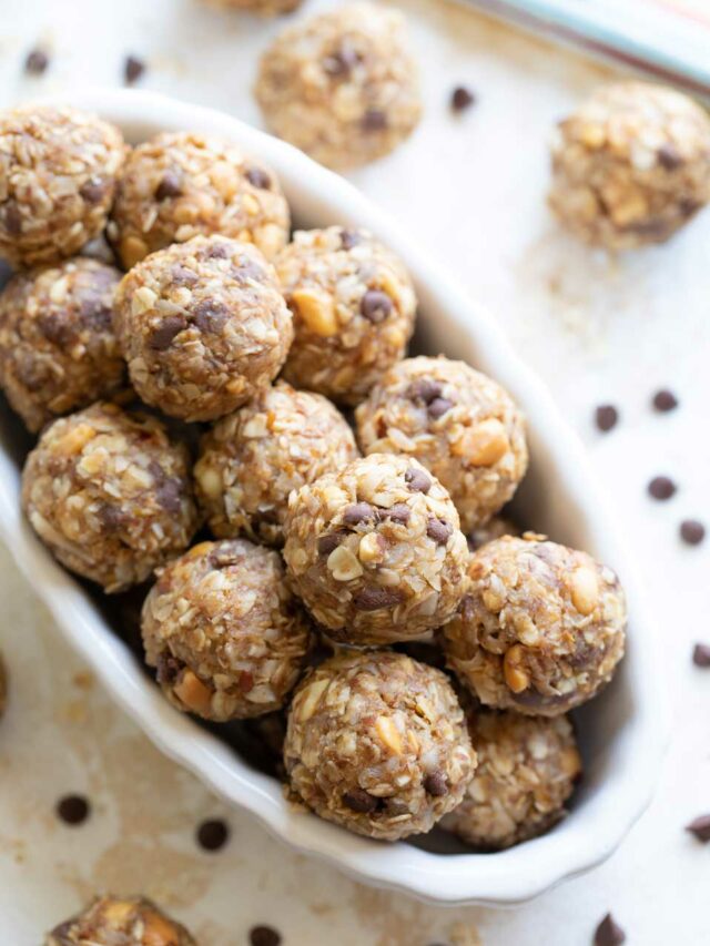 Oblong bowl piled with energy balls, with other bites laying in background nearby.