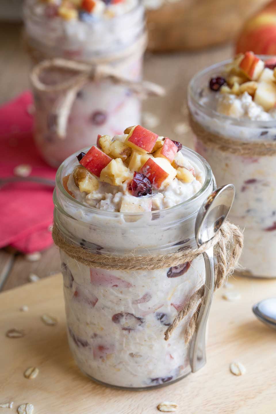 Side view of the Overnight Oats in jars, with a disposable spoon tied on and extra apple toppings.