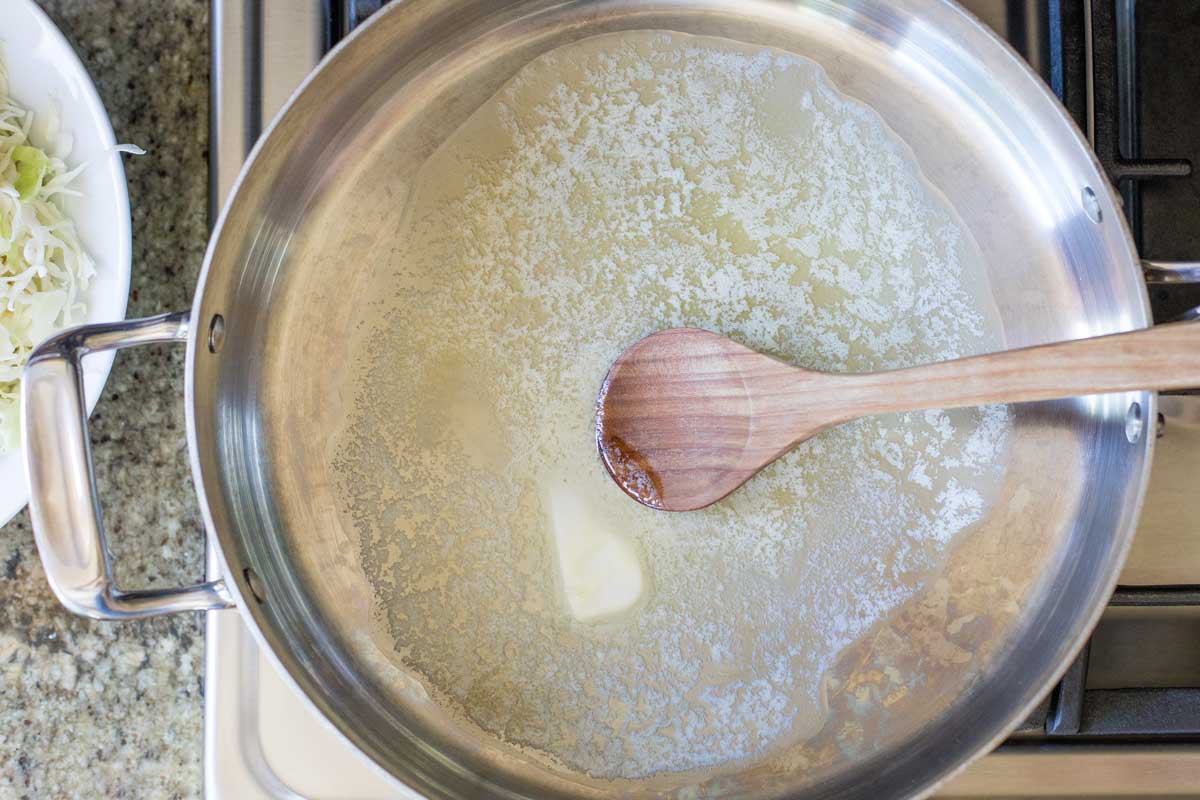 Overhead of saute pan on stove as butter begins to melt.