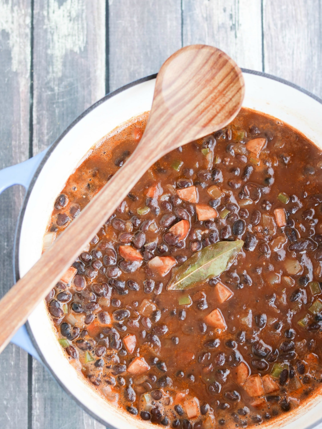 Cropped overhead of soup in pot with wooden spoon across it.