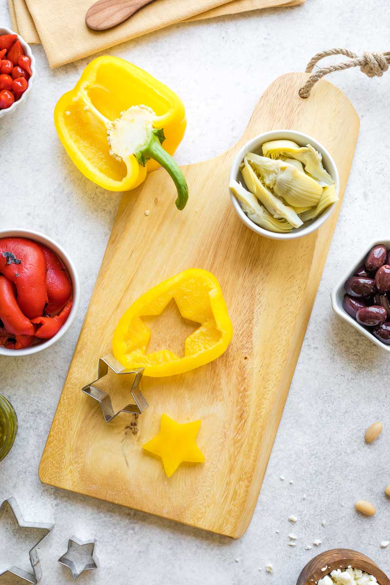 Overhead showing how to cut Christmas tree star out of yellow pepper with cookie cutter.
