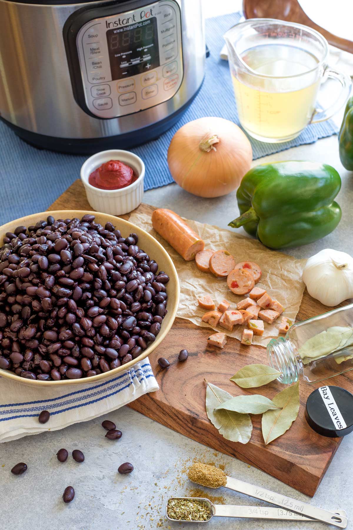 Recipe ingredients like black beans, sausage and spices prepped on cutting board with Instant Pot waiting in background.