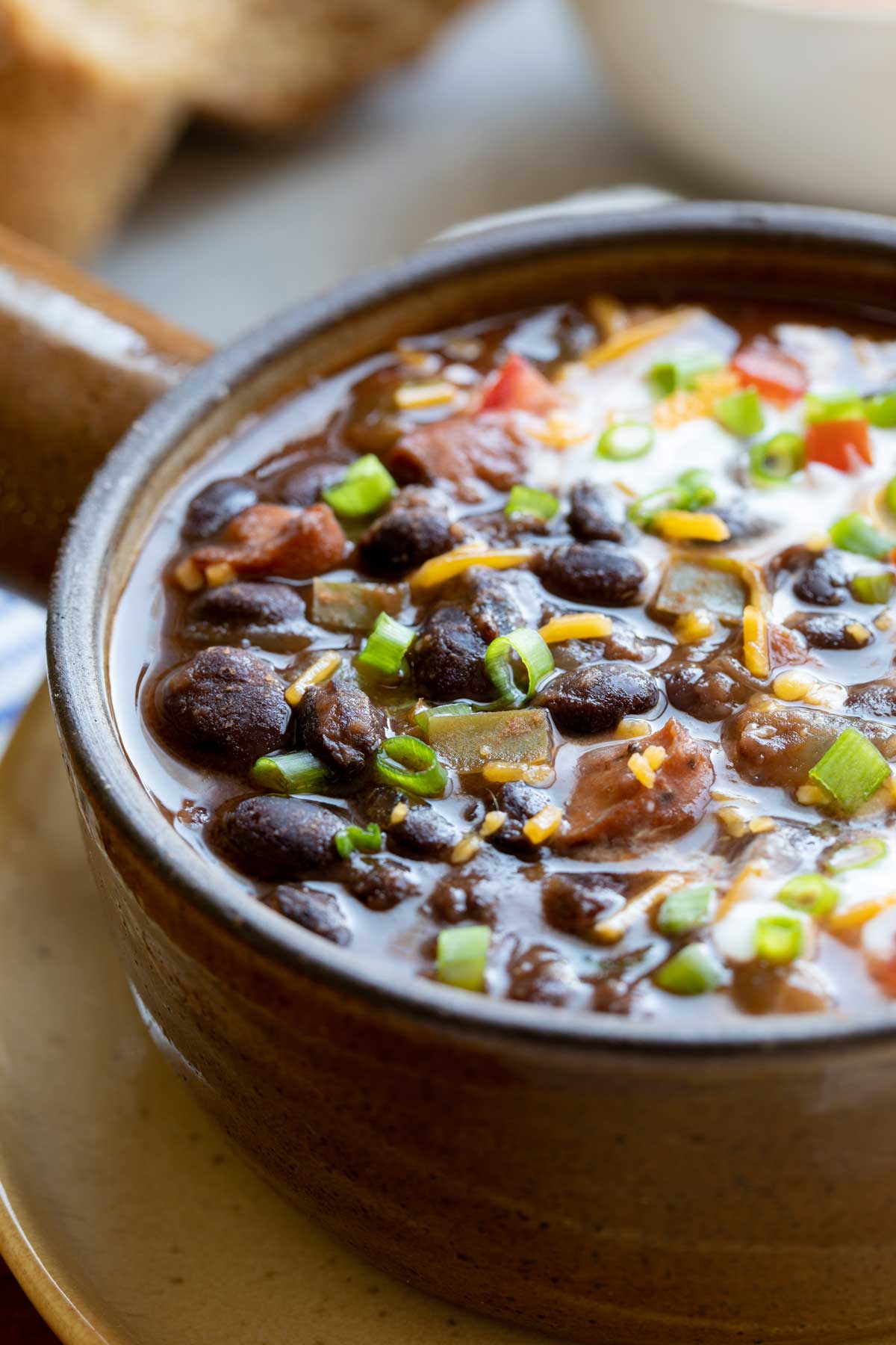 Closeup of soup served in crockery bowl, so you can really see the texture of the black beans and sausage.