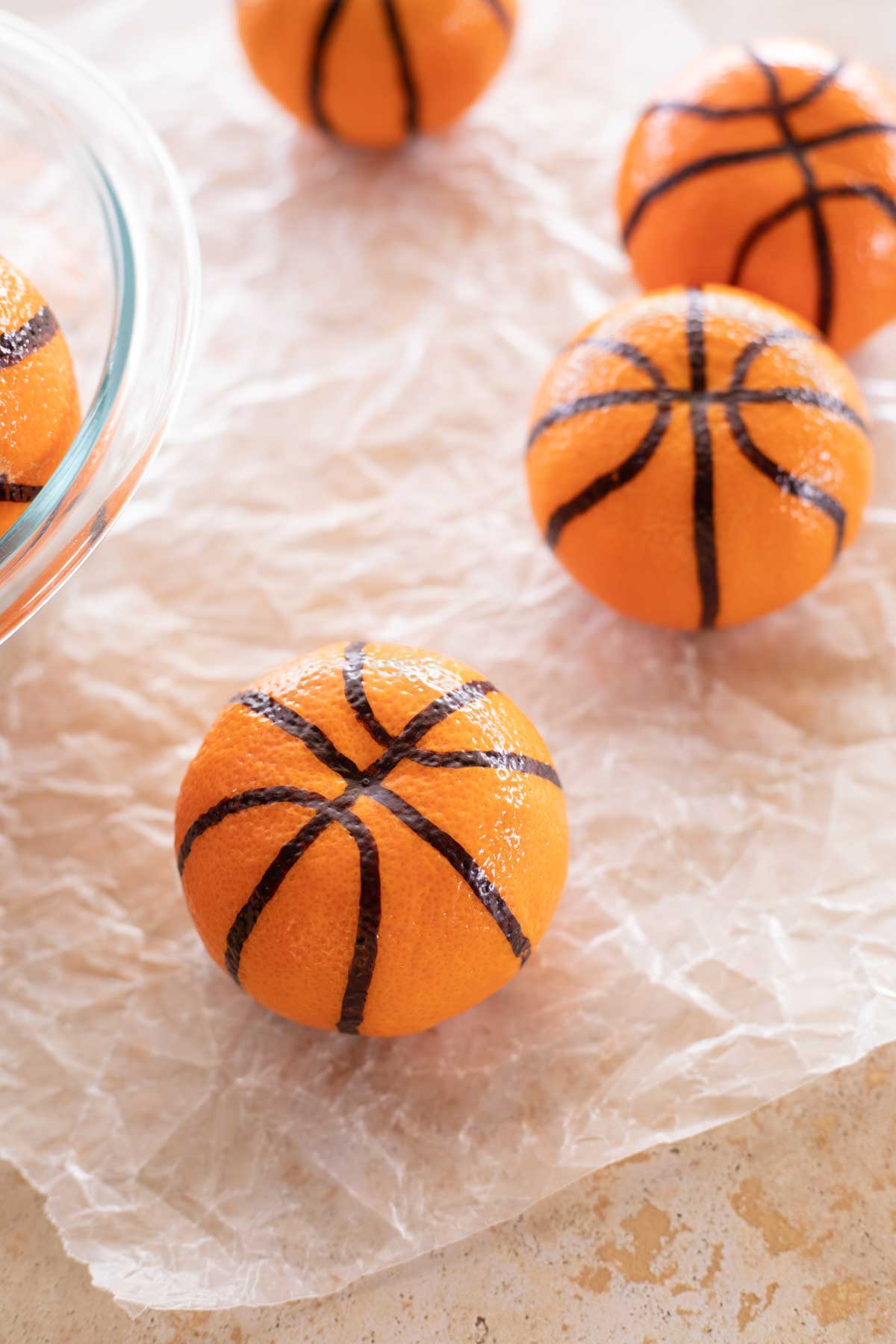 Closeup of a clementine that's been made into a basketball with others in background.
