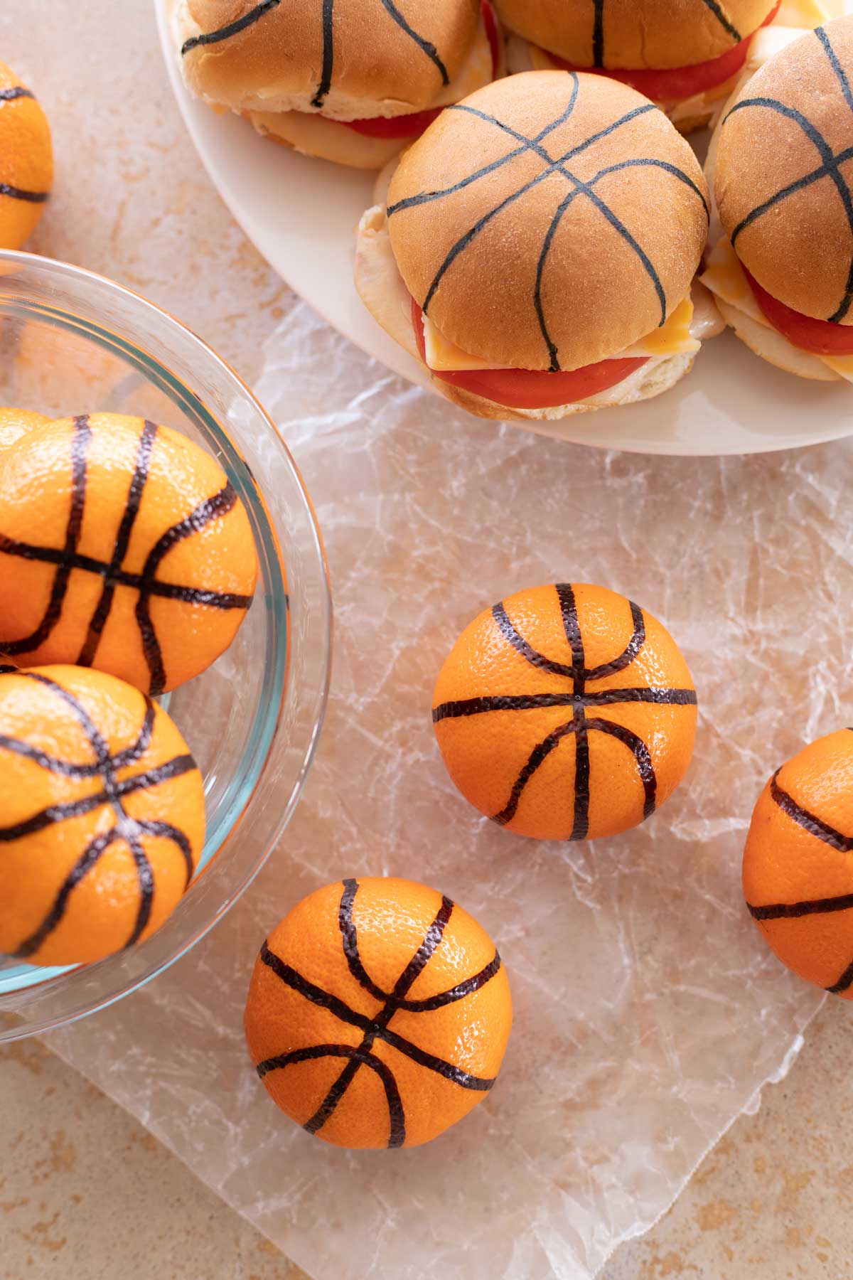 Overhead of several clementine basketballs with a platter of decorated sliders in background.