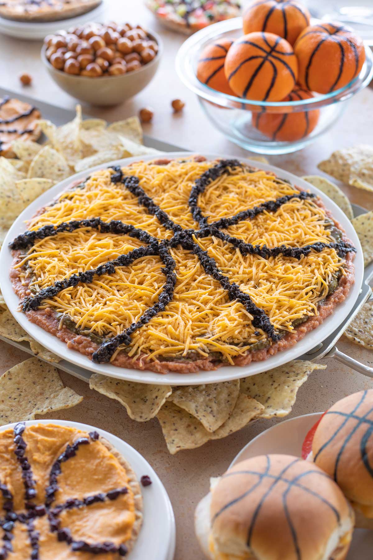 Layered Mexican Dip in center of other March Madness themed party foods.