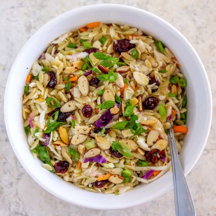 Overhead of vegan pasta salad recipe in white bowl with spoon tucked in.