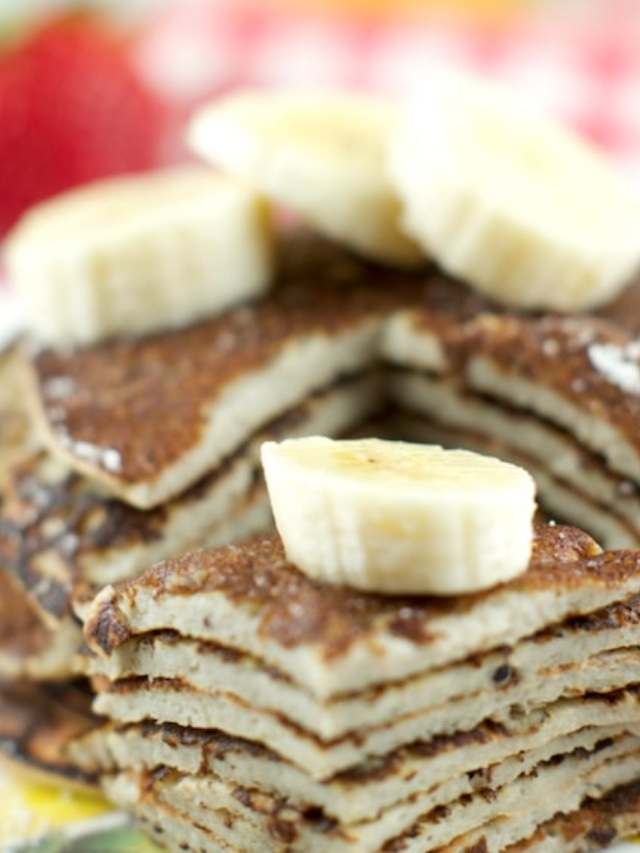 Closeup of stack of pancakes with banana slices on top.