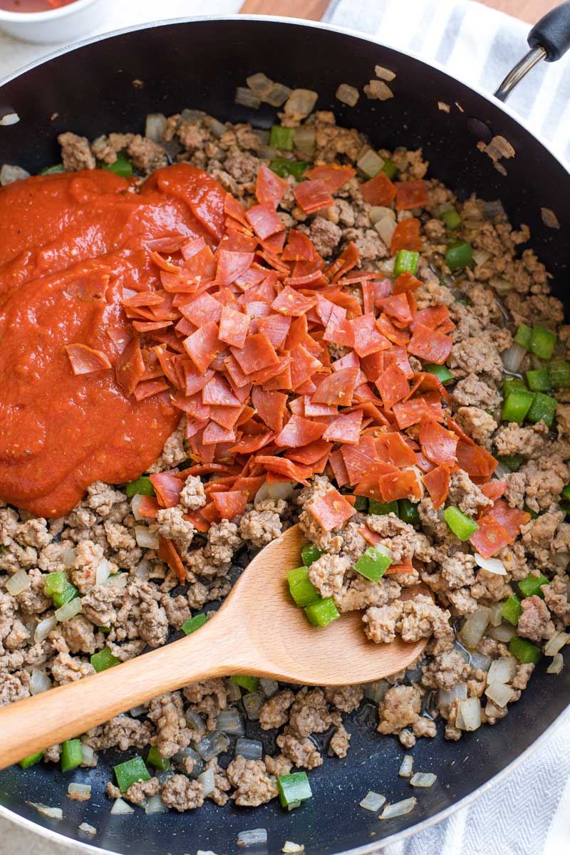 Sloppy joe sauce and pepperoni added to skillet with cooked meats.