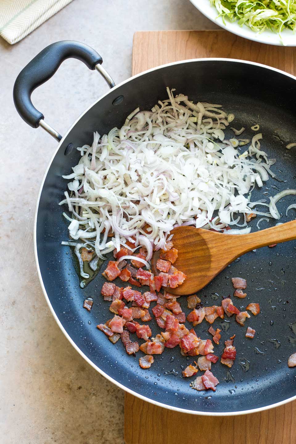Shredded shallots added to pan with sauteed bacon.