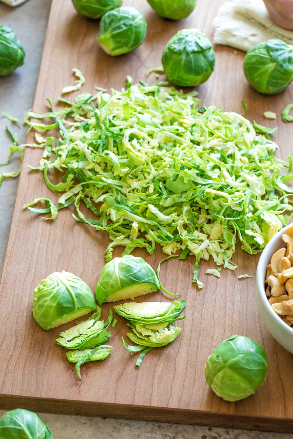 A pile of shredded Brussel sprouts, with two sprouts partially cut, showing how to shred them.