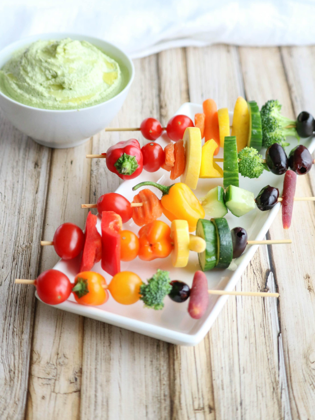 Rainbow Veggie Kabobs Cover Image with 5 skewers across white platter and dip in background.