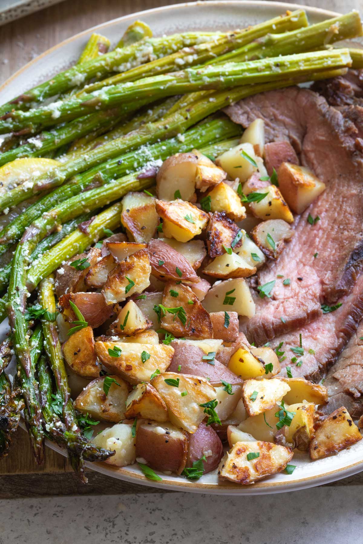 Dinner plate with potatoes, asparagus and grilled steak slices.