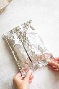 Two hands making final crimp in end of foil packet.