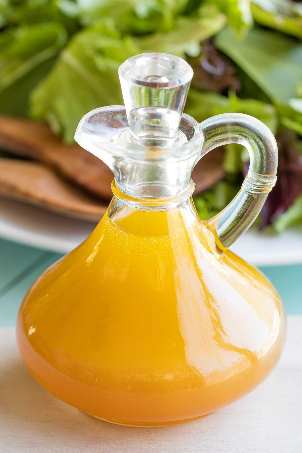 Cruet of Honey Balsamic dressing with salad in background.