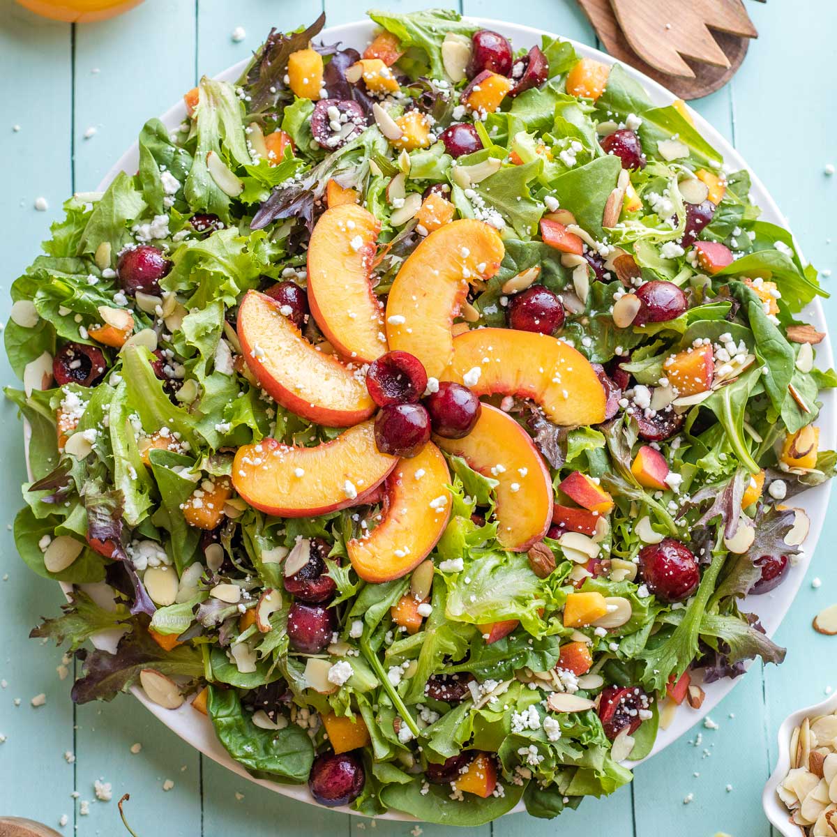 Finished salad on serving platter with sunshine made out of peaches decoratively at center.