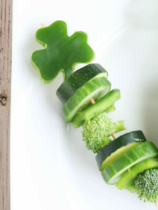 Closeup of one shamrock cut from green pepper on top of skewer with various green vegetables.