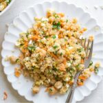 Closeup of final quinoa salad served on decorative plate with pretty fork tucked into it.