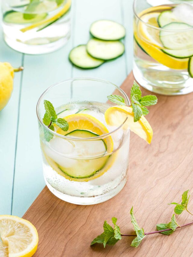 Several glasses of the finished recipe arranged with extra ingredients scattered nearby and also added as garnishes to the water.