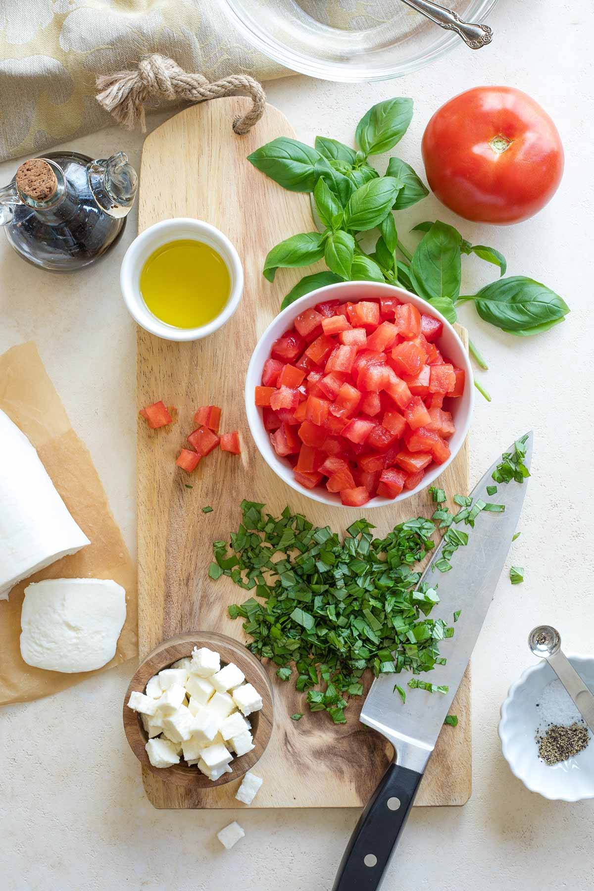 Chopped ingredients for the Italian caprese topping, arranged on cutting board with knife.