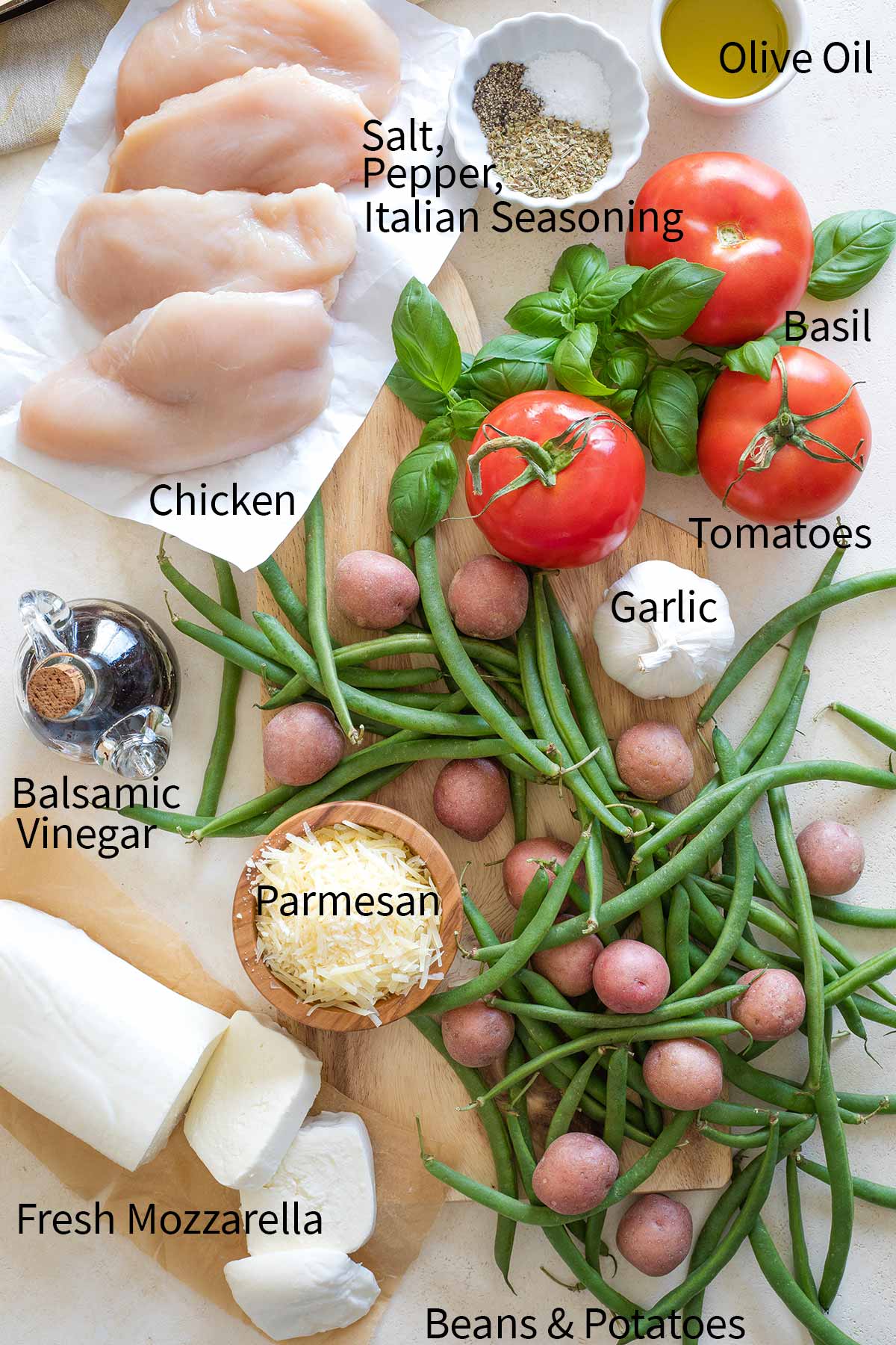 Overhead of all labeled recipe ingredients: (clockwise) Olive Oil, Basil, Tomatoes, Garlic, Beans & Potatoes, Fresh Mozzarella, Parmesan, Balsamic Vinegar, Chicken, Salt, Pepper, Italian Seasoning.