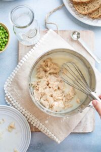 Tuna being added to cream sauce and whisked in.