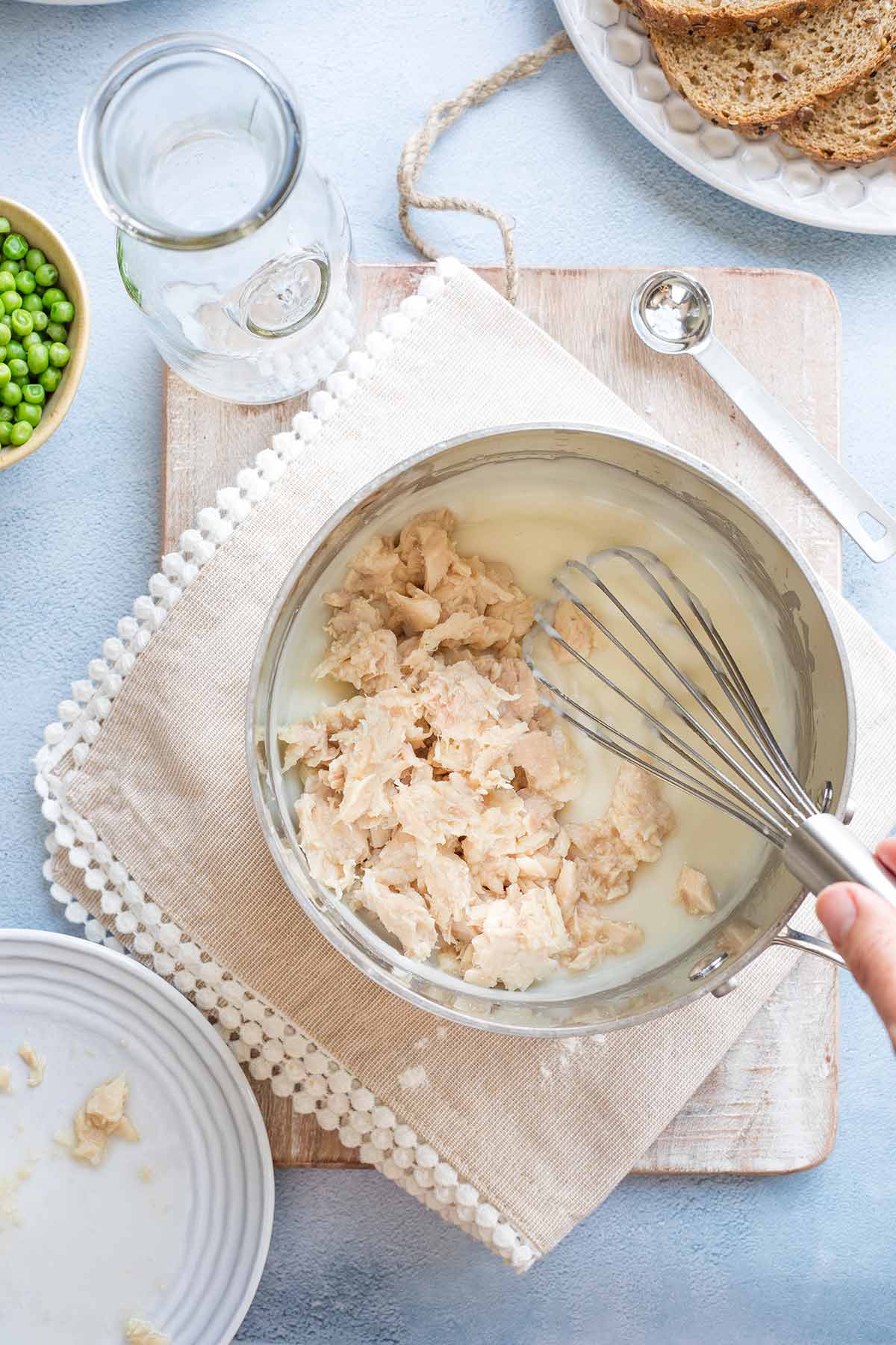 Tuna being added to cream sauce and whisked in.