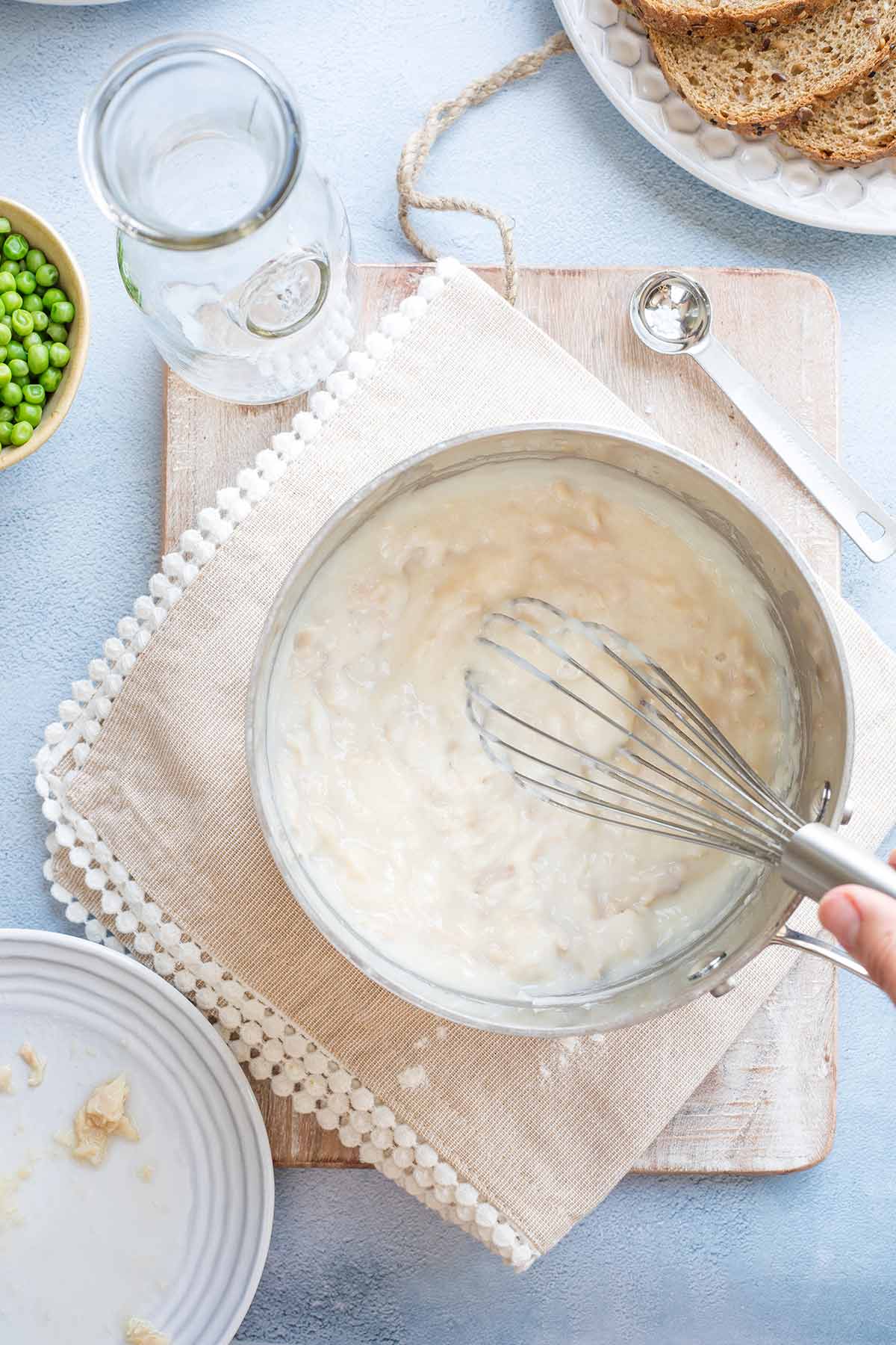 Hand whisking finished creamed tuna sauce in pan.