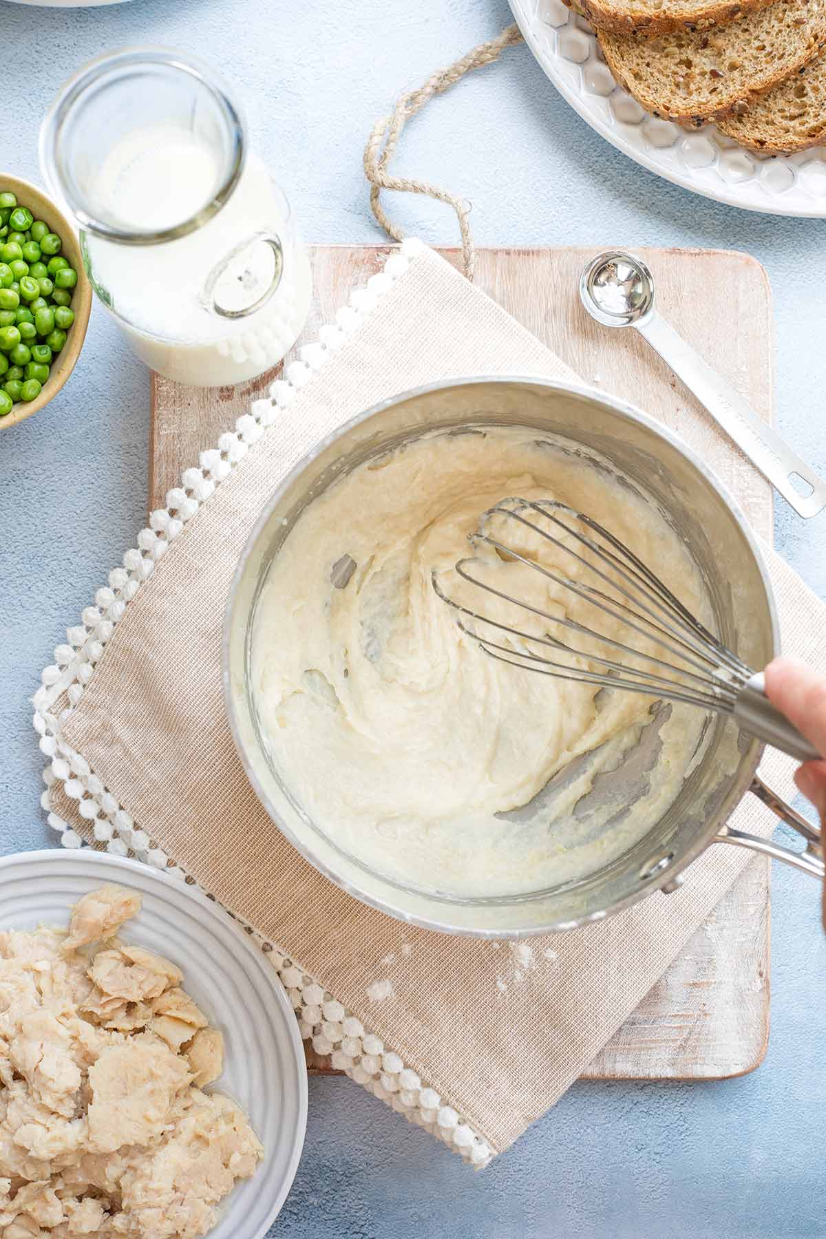 Hand whisking cream sauce in pan.