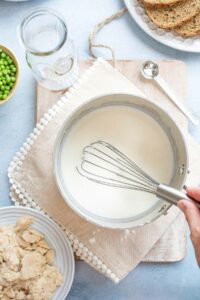 Hand whisking after last addition of milk to tuna cream sauce, while it is still very thin.