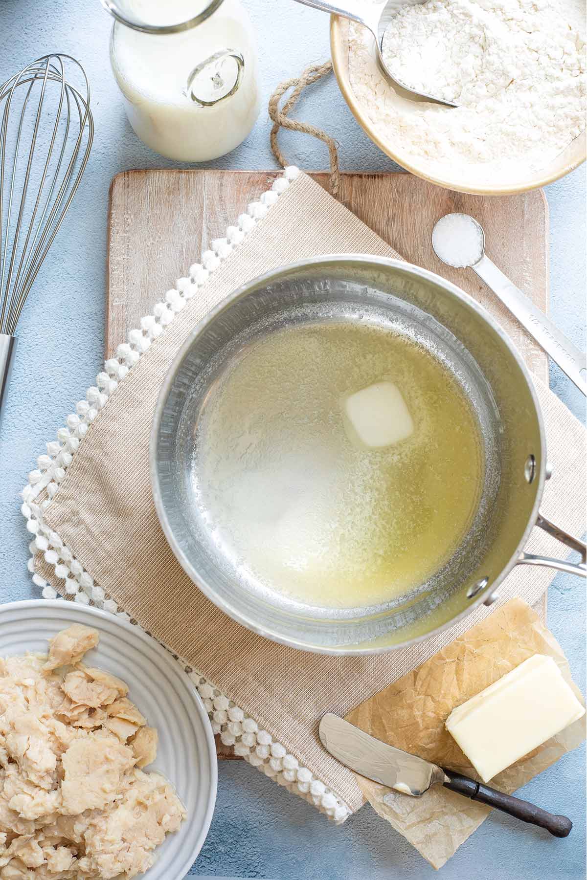 Step 1 overhead of butter melting in pan with tuna, butter, milk, flour and salt ready nearby.