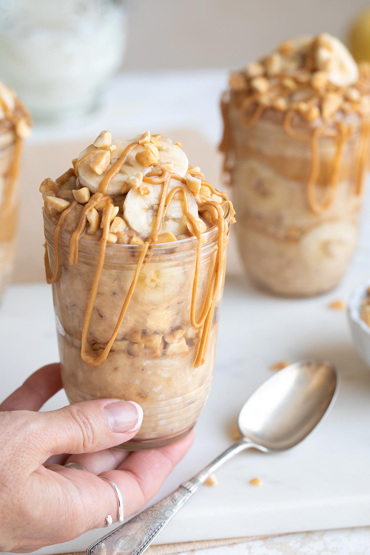 Hand holding up one jar full of overnight oats so you can see the layers from the side.