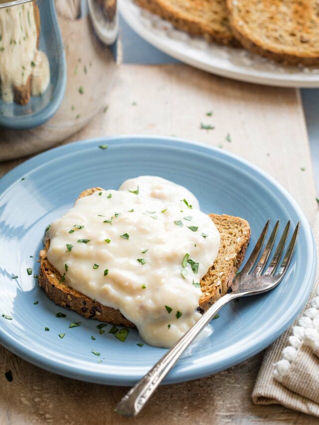 "Basic" recipe with creamed tun spooned over a piece of toast on a blue plate with fork; pan and toast sliced in background.