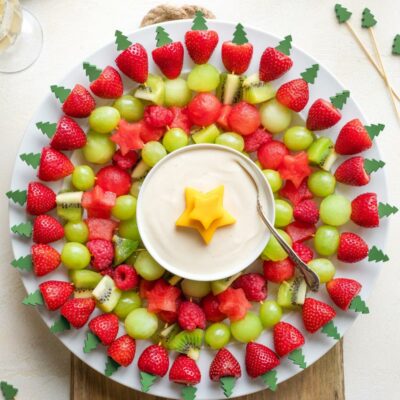 Overhead of finished Christmas wreath made of fruit kabobs around a dish or fruit dip.