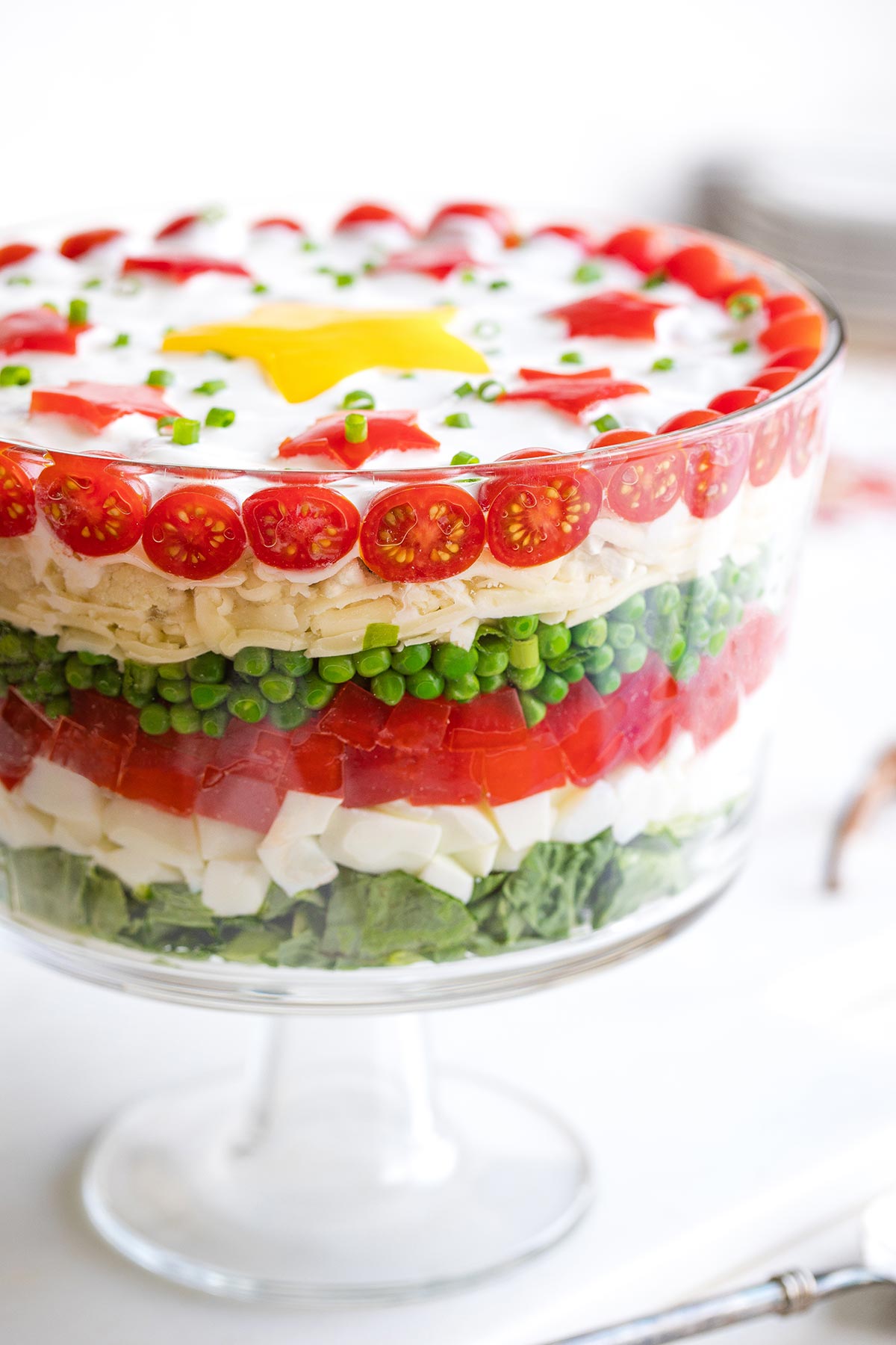 Side view of salad in footed glass potluck bowl so you can see the 7 layers of Christmas colors.