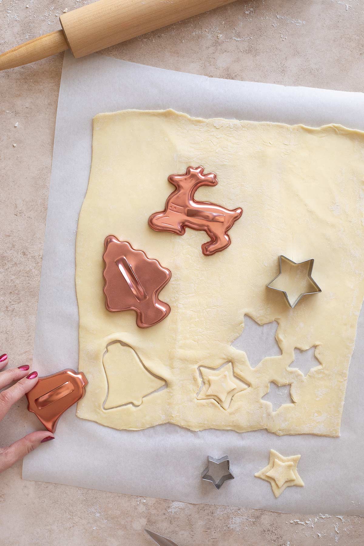 Various Christmas-themed cookie cutters cutting out puff pastry decorations that could be used for Wellingtons at Christmas time.