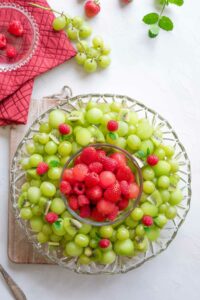 Finished wreath with additional red fruits piled into the bowl at the center of the platter.