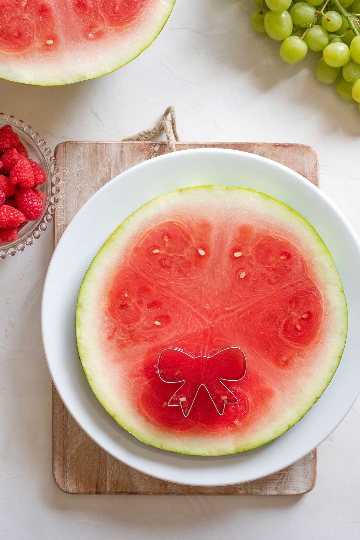 Bow-shaped cookie cutter on top of watermelon plank.