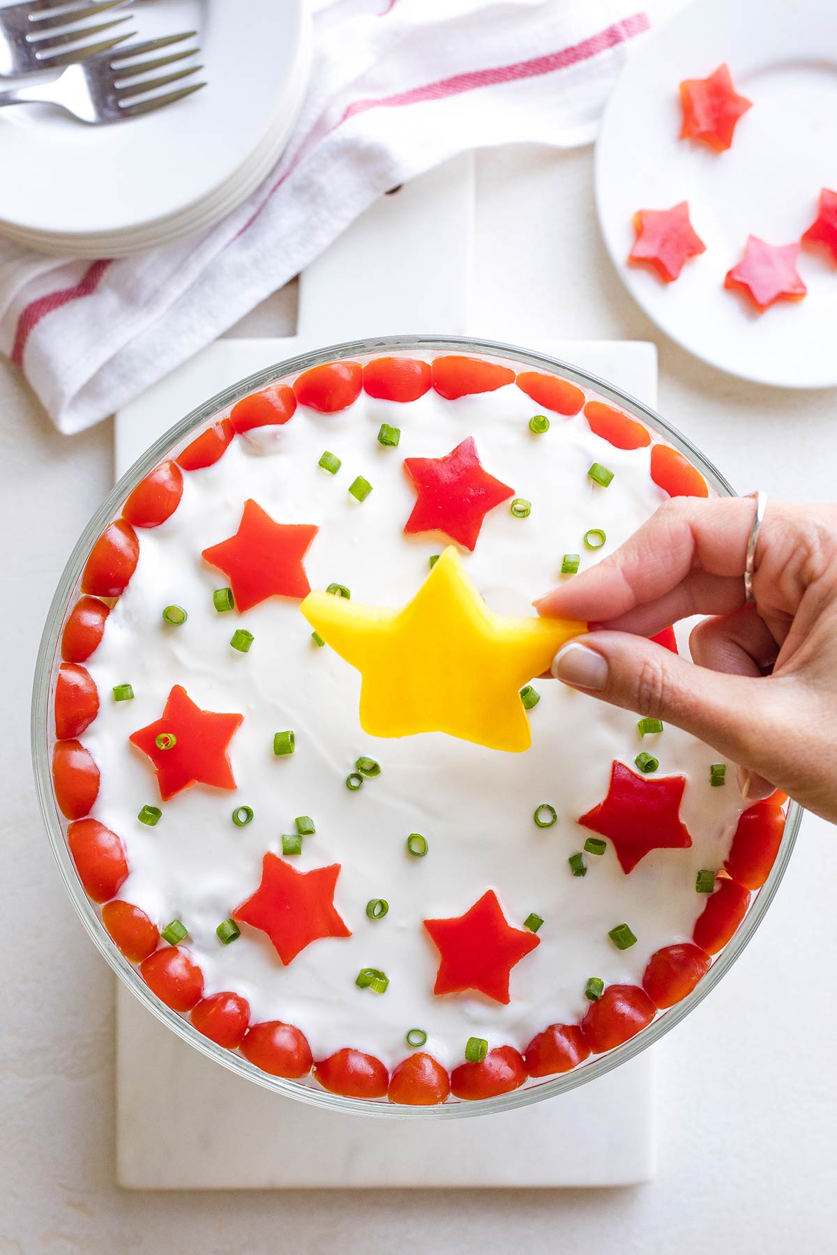 Hand placing central gold star decoration on top of salad dressing layer.