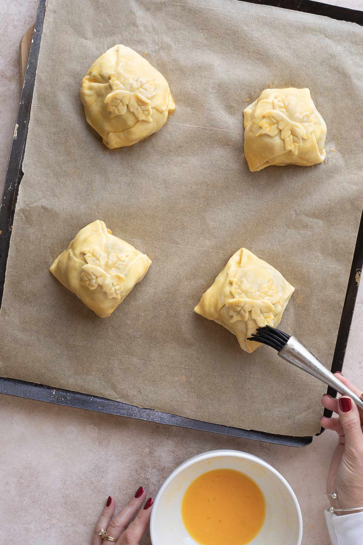 Pastry brush coating each individual beef Wellington completely in egg wash before baking.