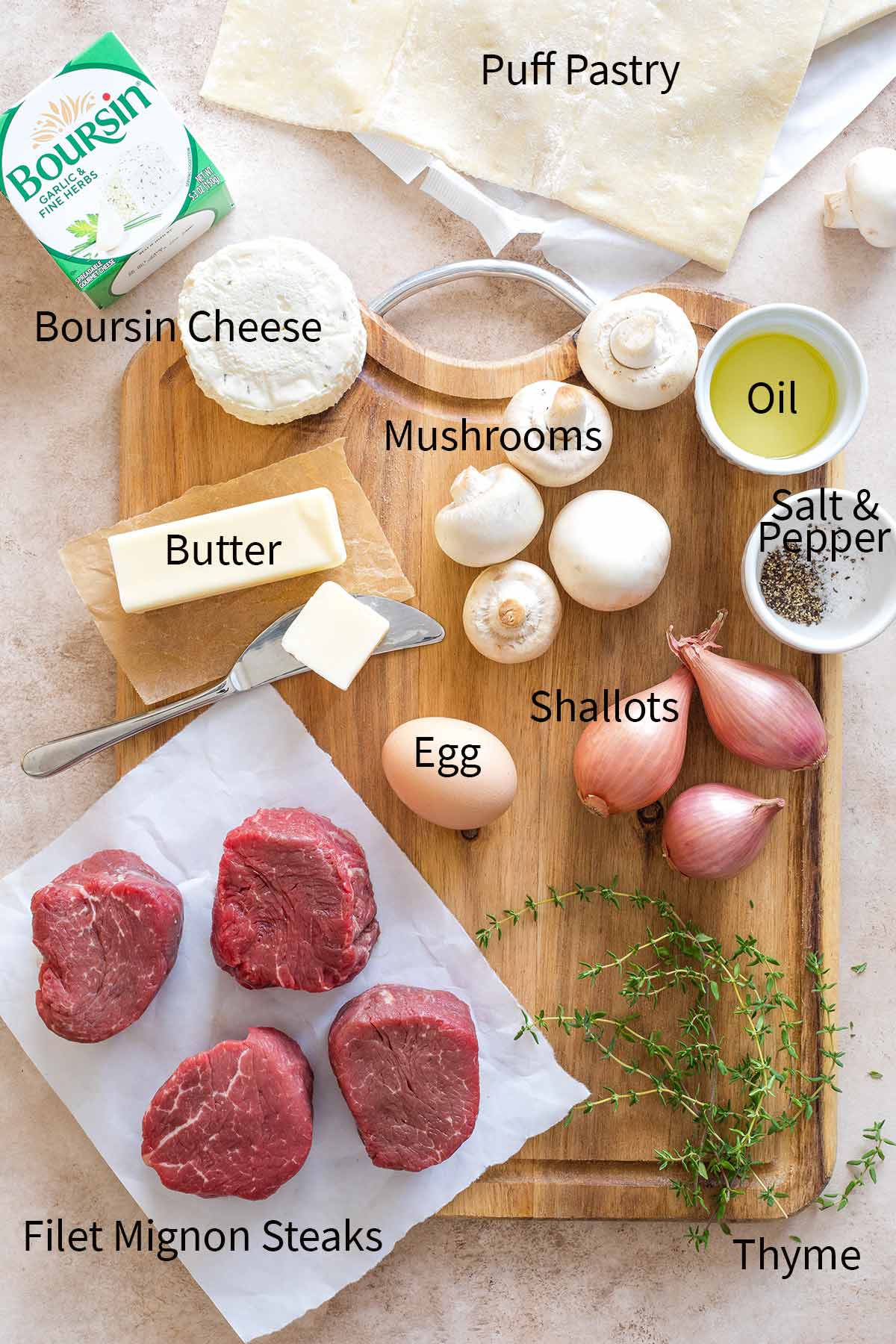 Photos of recipe ingredients with labels (clockwise): Boursin Cheese, Mushrooms, Puff Pastry, Oil, Salt & Pepper, Shallots, Thyme, Filet Mignon Steaks, Egg, Butter.