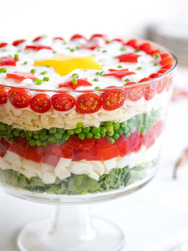 Side view of salad in footed glass potluck bowl so you can see the 7 layers of Christmas colors.