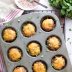 Muffin pan of baked Mexican meatloaf minis, with cilantro and dish of Creamy Salsa Sauce for topping.